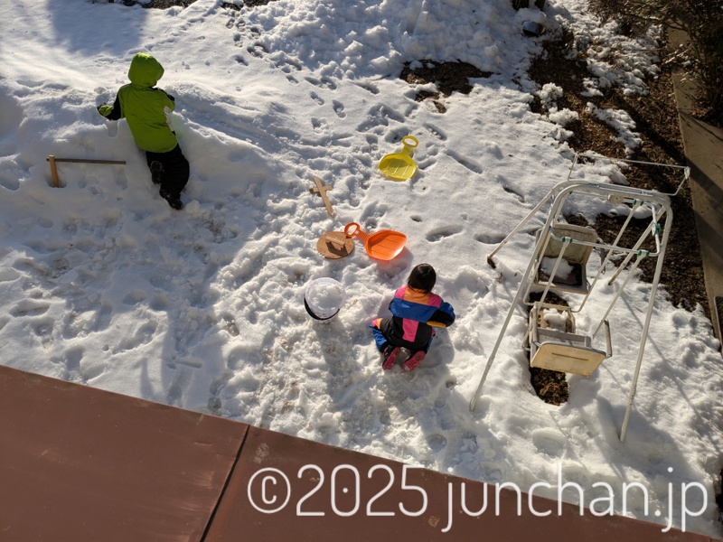 庭の雪で遊ぶ子どもたち